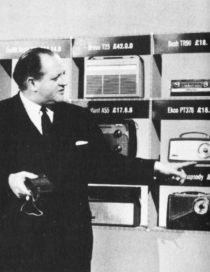Dimbleby points to various transistor radios, their prices marked in £sd