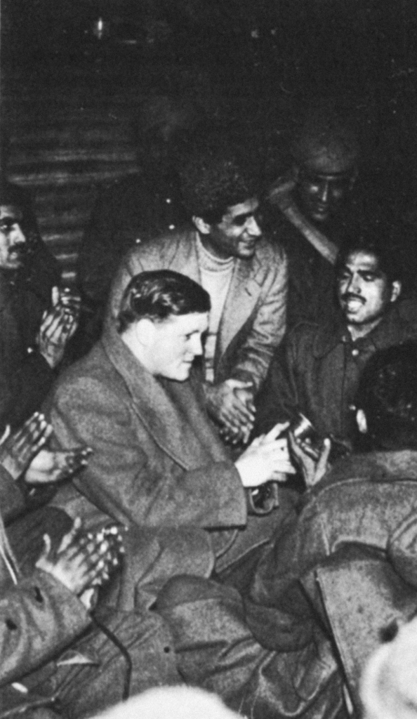 Dimbleby sits amongst a group of men