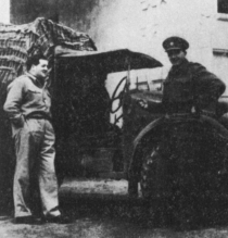Two men stand beside an open-sided car