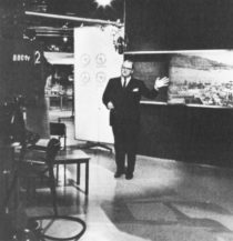 Dimbleby gestures to a photograph on the TV studio wall