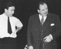 Two men, one is shirtsleeves, one in a suit