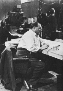 Dimbleby in shirtsleeves works at a desk