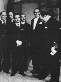 Six men in formal suits stand on the set of 'Panorama'