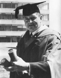 Dimbleby in gown and mortar holding his doctorate